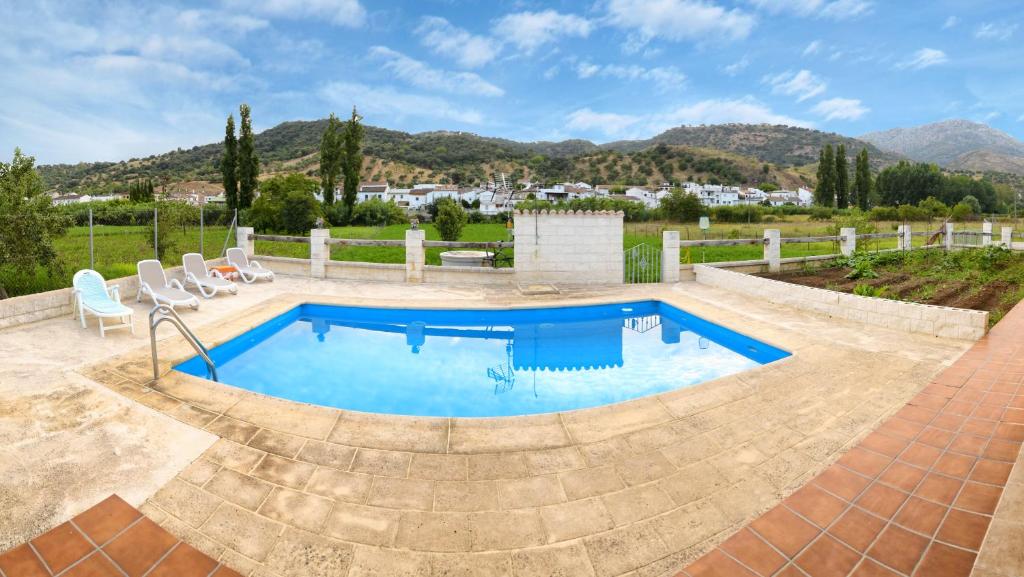 una piscina en un patio con sillas alrededor en Casa Rural "Allán frente", en Cortes de la Frontera