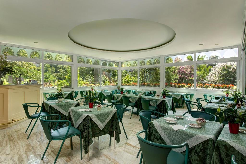 a restaurant with green tables and chairs and windows at Hotel Biasutti in Venice-Lido