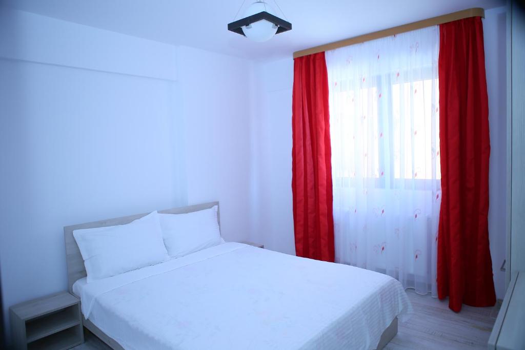 フォクシャニにあるRCC Apartamentsの白いベッド(赤いカーテン付)