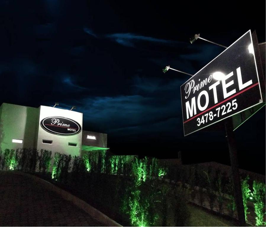 a sign that reads drink motel at night at Prime Motel in Criciúma