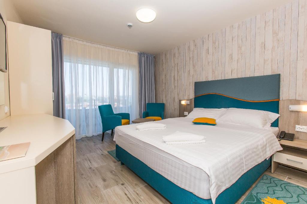 a bedroom with a large bed and blue chairs at Hotel Riviera in Mamaia