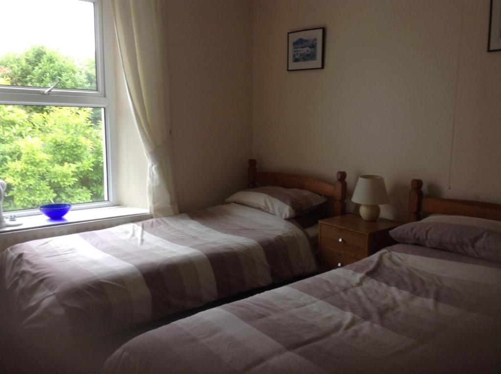 two beds in a room with a window at Drakewalls Bed And Breakfast in Gunnislake