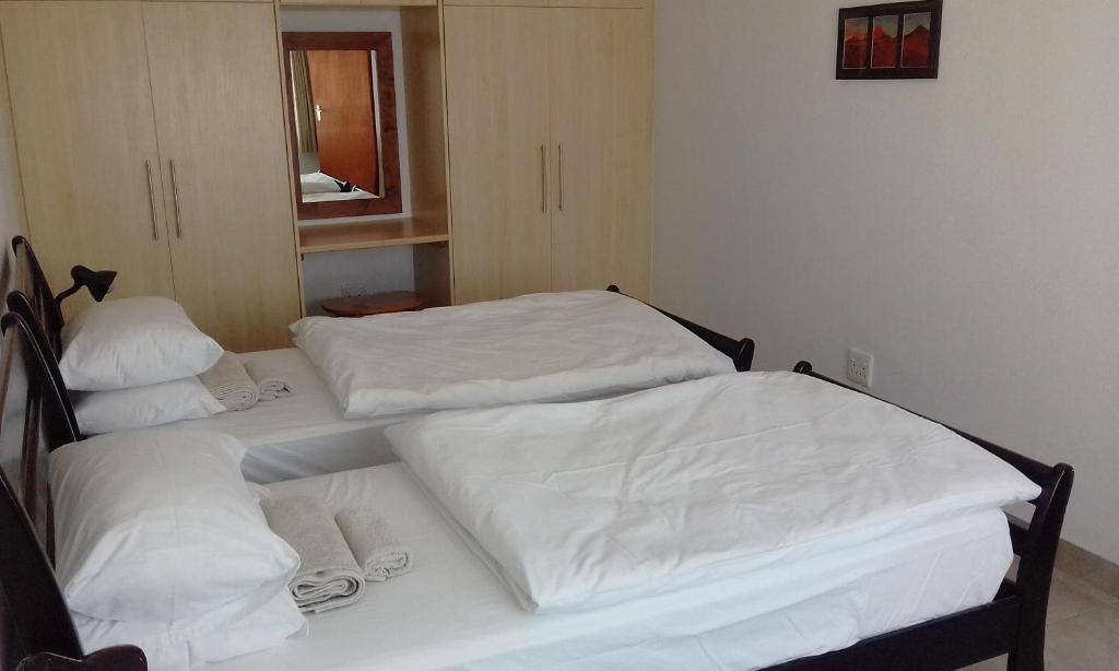 two beds in a room with white sheets at Maggie´s Accommodation in Swakopmund