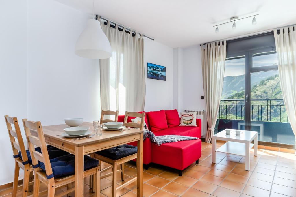 a living room with a table and a red couch at Apartamentos Prat de les Molleres in Soldeu