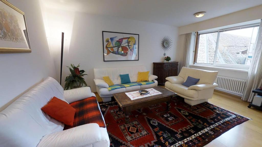 una sala de estar con 2 sofás blancos y una mesa. en Paravicini, en St. Moritz