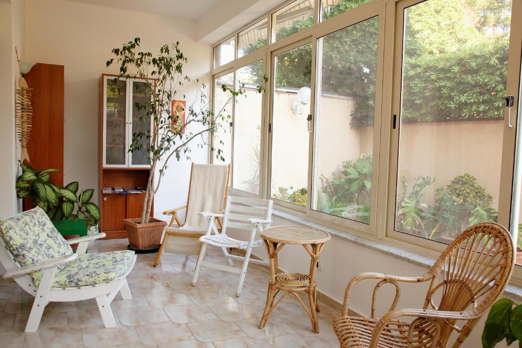 Zimmer mit Stühlen, einem Tisch und Fenstern in der Unterkunft Siciliaiu in Mondello