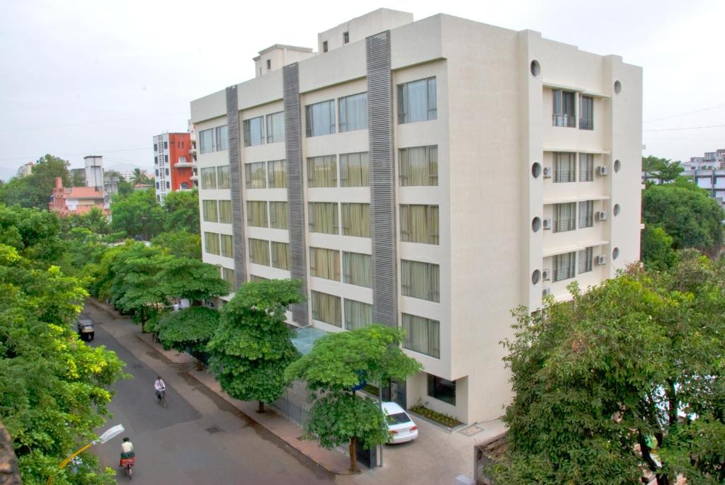 biały budynek z drzewami przed nim w obiekcie Shantai Hotel w mieście Pune