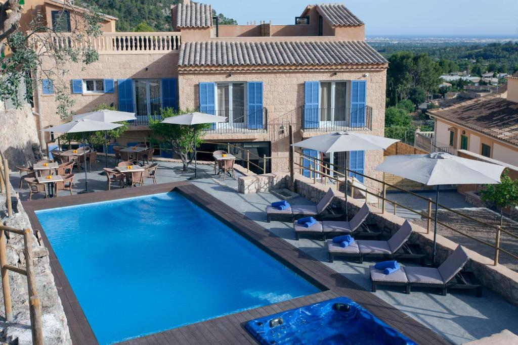 an outdoor pool with chairs and umbrellas next to a house at Es Corte Vell - Adults Only in Bunyola