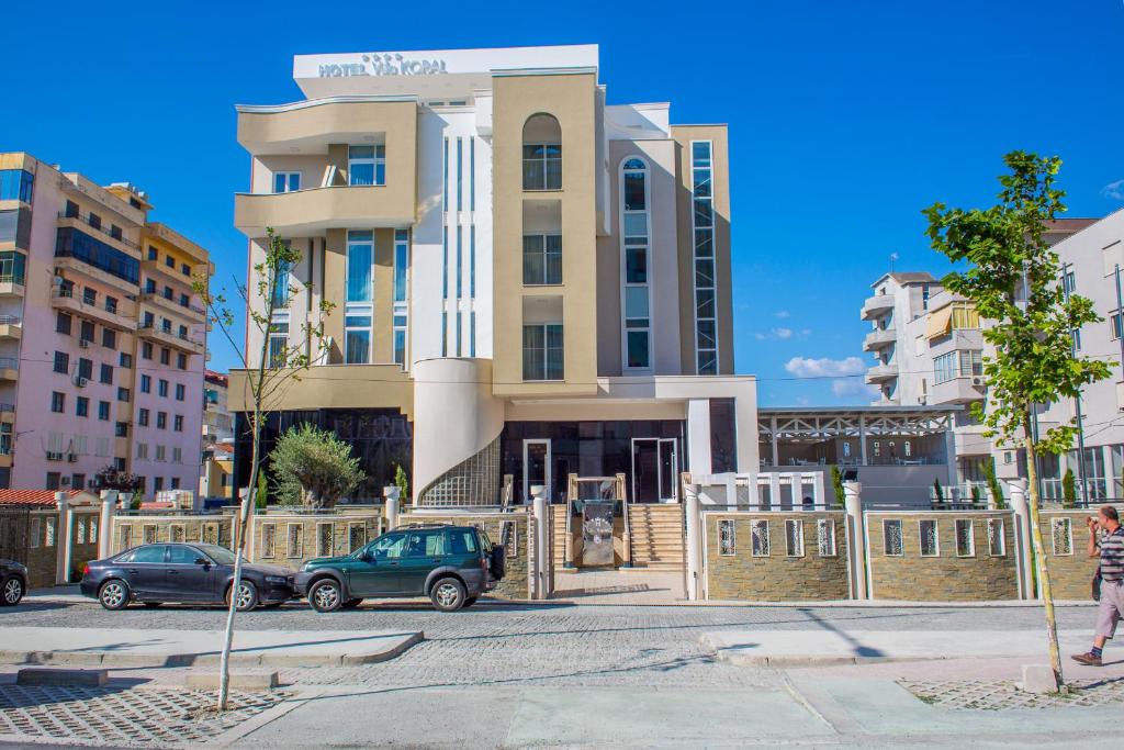 a building with cars parked in front of it at Hotel Vila Koral in Durrës