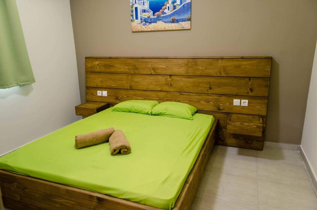 a bed with green sheets and two towels on it at Maestro Apartments Faliraki in Faliraki