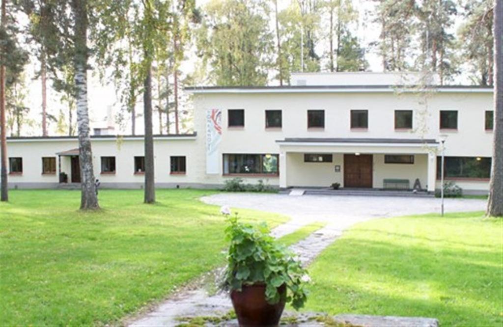 a white building with a potted plant in front of it at Art Hotel Honkahovi in Mänttä