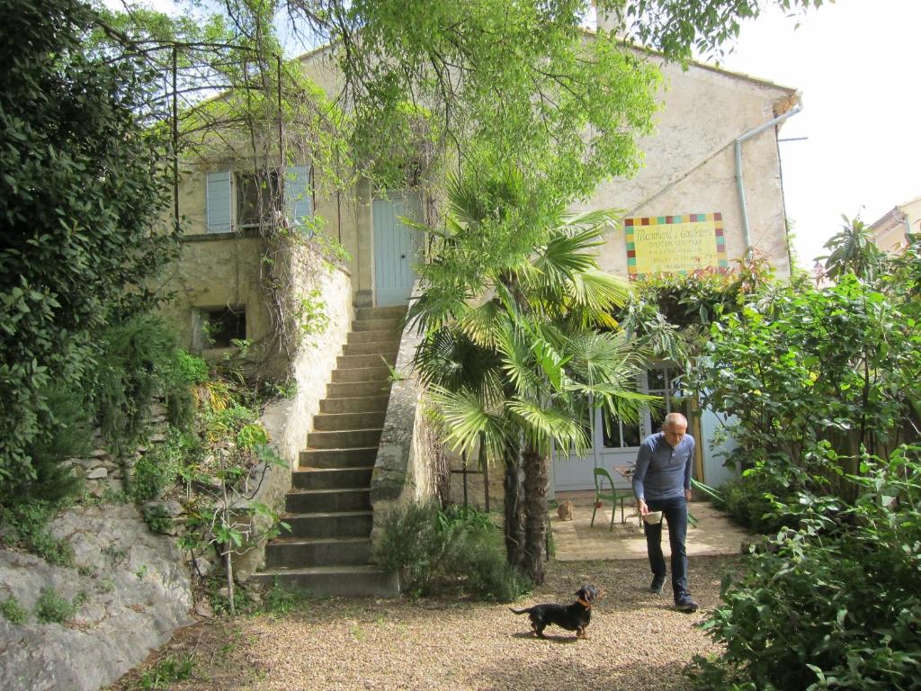 a man walking a dog in front of a building at La Maison des Couleurs in Saint-Saturnin-lès-Apt