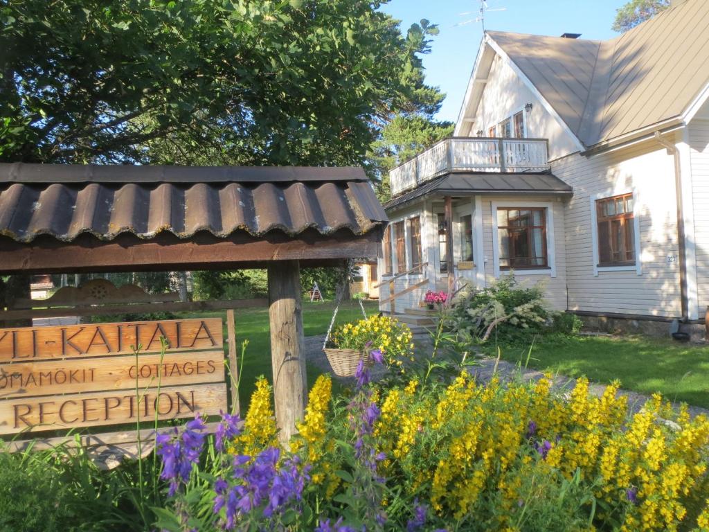 a sign in front of a house with flowers at Yli-Kaitala Holiday Resort Tuuliviiri in Savio