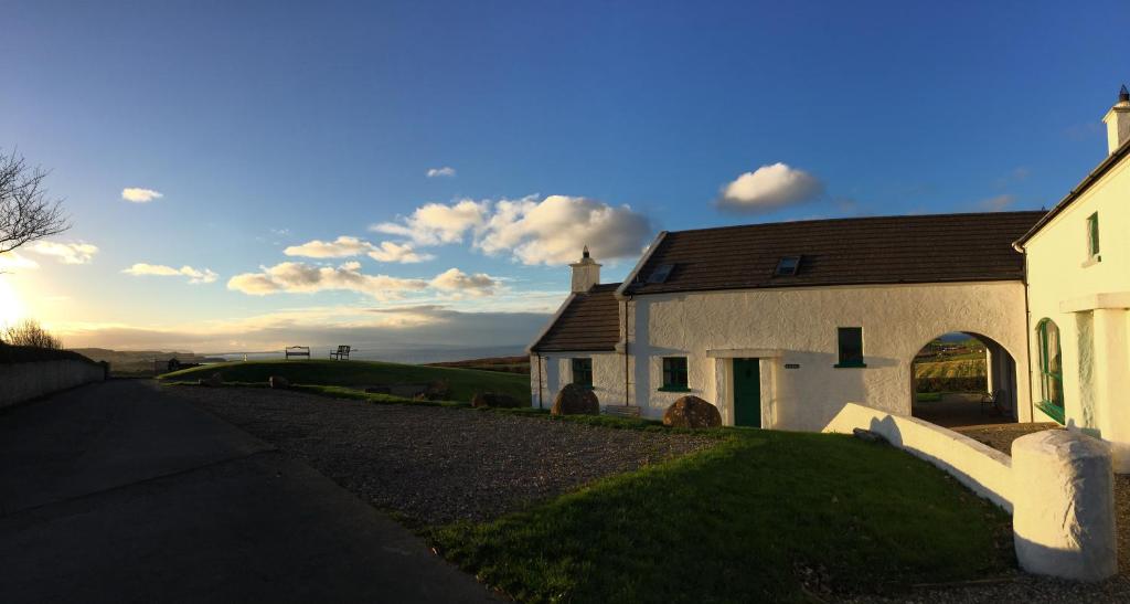 una iglesia blanca con una colina al fondo en Ballylinny Holiday Cottages, en Bushmills