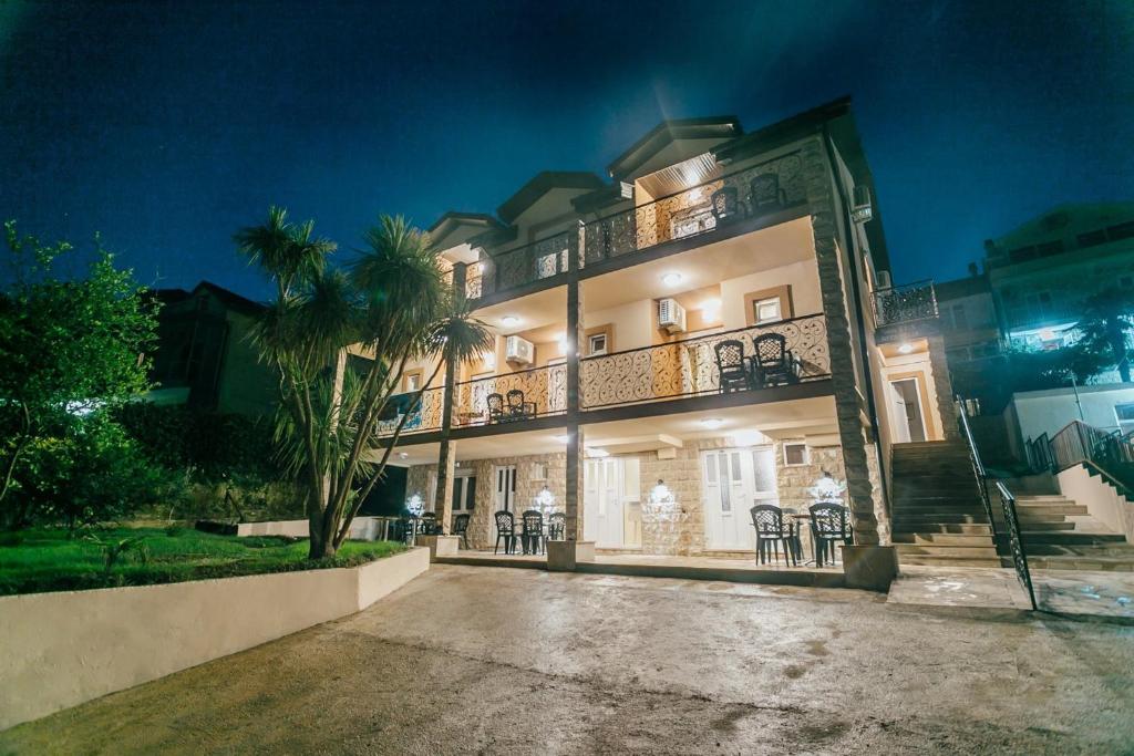 Un grand bâtiment blanc avec balcon est disponible la nuit. dans l'établissement Apartments Belani, à Herceg-Novi