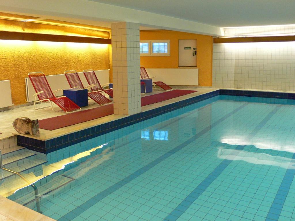 einen großen Pool mit Stühlen in einem Zimmer in der Unterkunft Hotel Meran Hallenbad & Sauna in Saarbrücken