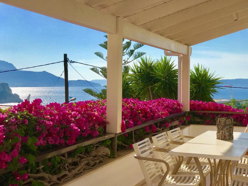 een patio met roze bloemen en een tafel en stoelen bij Almyrida Sands in Almirida