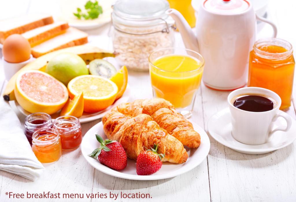 a breakfast table with croissants and fruit and juice at Days Inn & Suites by Wyndham Langley in Langley