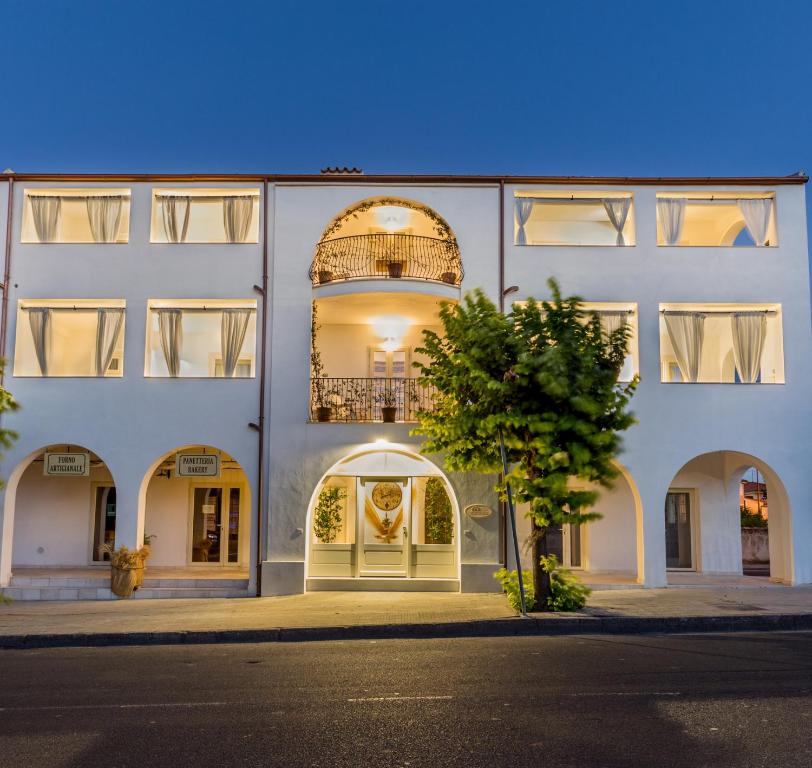 a white building with an arch doorway and a tree at Mannois - Lofts & Apartments in Orosei