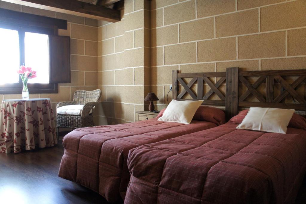 sypialnia z 2 łóżkami i ceglaną ścianą w obiekcie Casa Rural Estrela w mieście San Martín de Trevejo