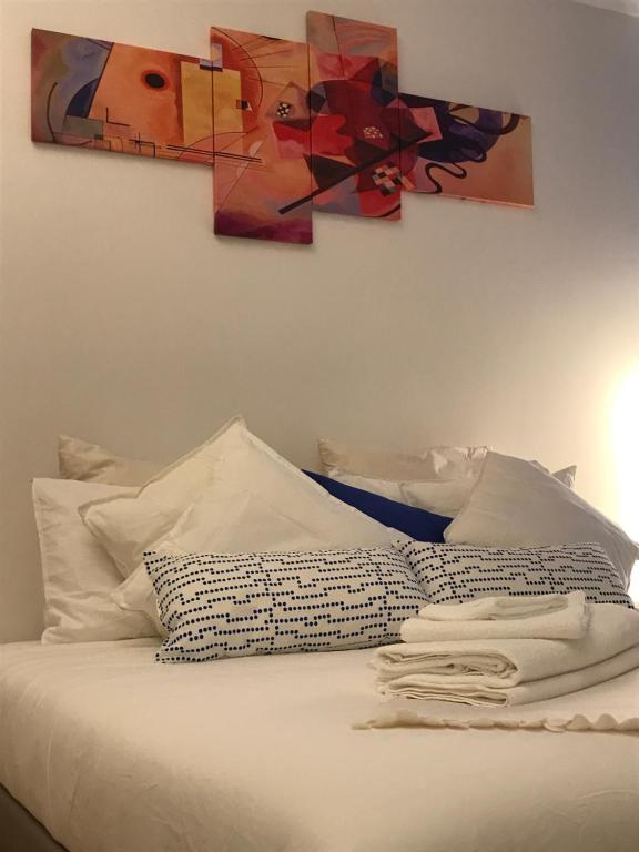 ボローニャにあるI love my Houseの白い枕と壁に絵画が飾られたベッド