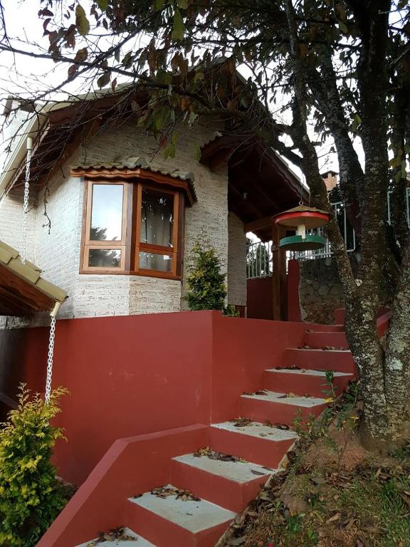 a house with a red fence and a tree at Pousada Canto do Sabiá in Monte Verde