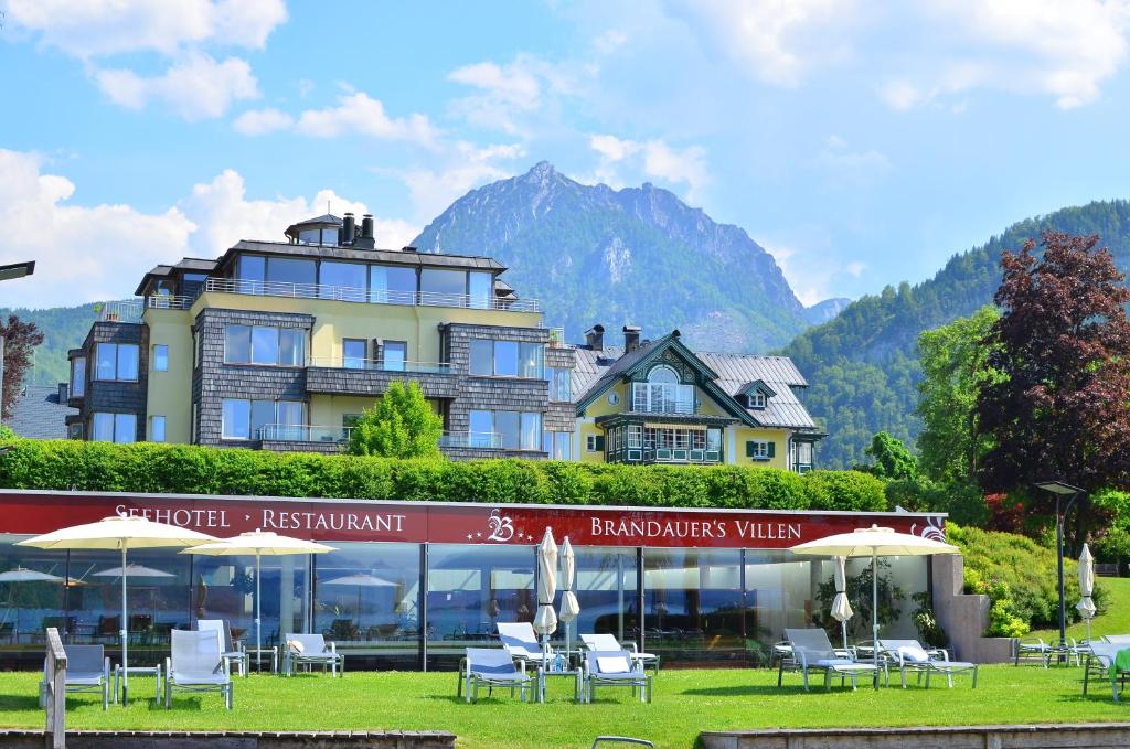 a hotel with tables and chairs in front of a building at Hotel Brandauers Villen Superior in Strobl