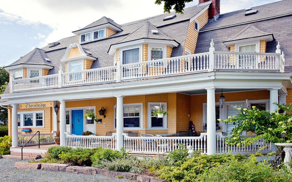 a large yellow house with a white balcony at Thornhedge Inn in Bar Harbor