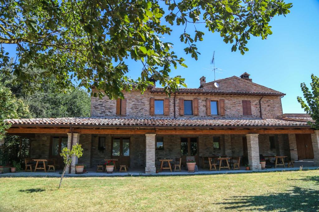 een oud huis met tafels en stoelen ervoor bij Agriturismo La Caputa in Urbania