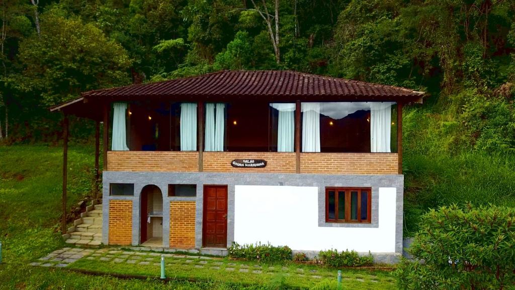 una pequeña casa con techo marrón en una colina en Spa e Hotel Fazenda Gaura Mandir en Teresópolis