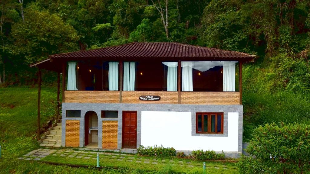 una pequeña casa con techo marrón en una colina en Spa e Hotel Fazenda Gaura Mandir, en Teresópolis