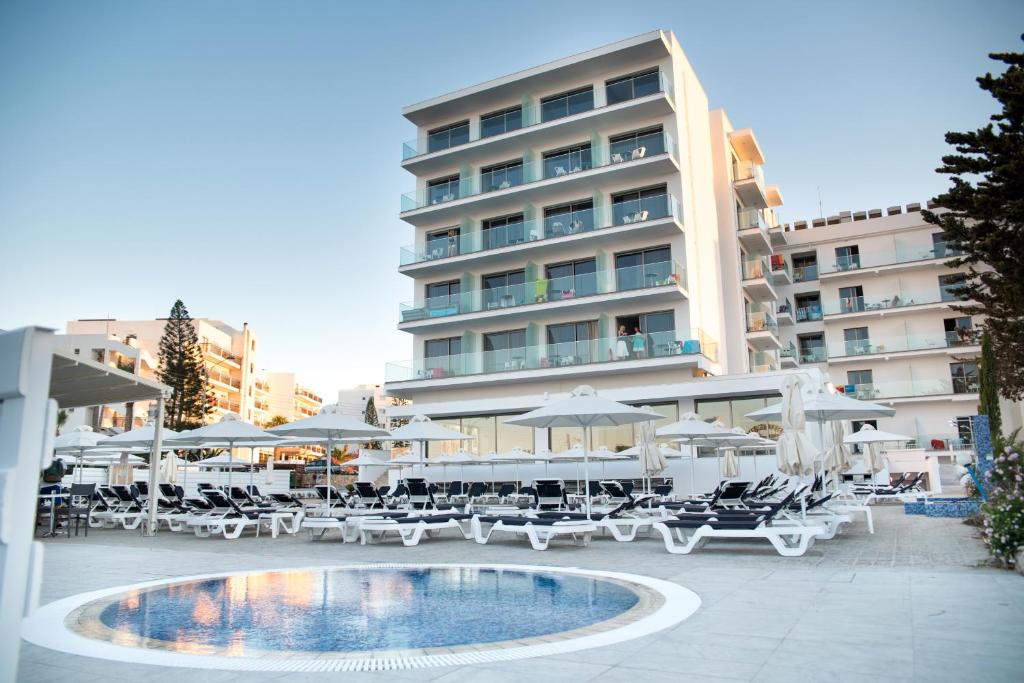 um hotel com piscina, cadeiras e guarda-sóis em Mandali Hotel em Protaras
