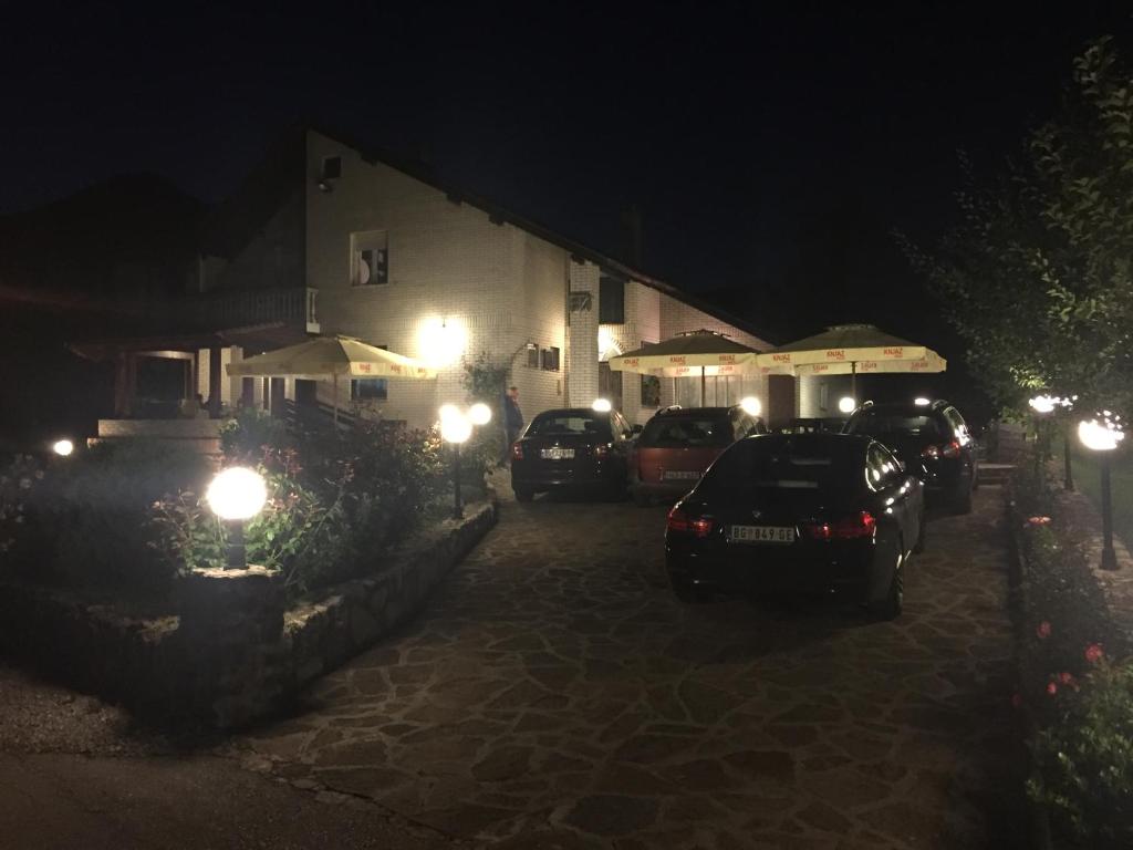 un gruppo di auto parcheggiate di fronte a un edificio di notte di Apartmani Berghaus a Zlatibor