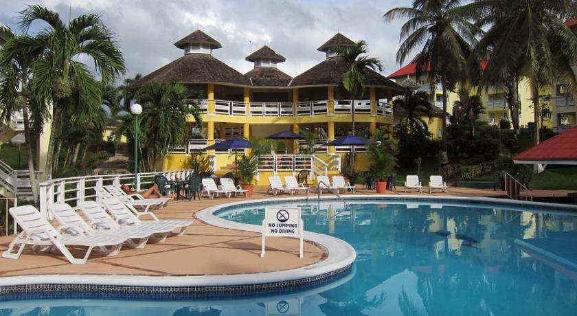 a resort with a pool and chairs and a building at Mystic Ridge Apt 26F in Ocho Rios