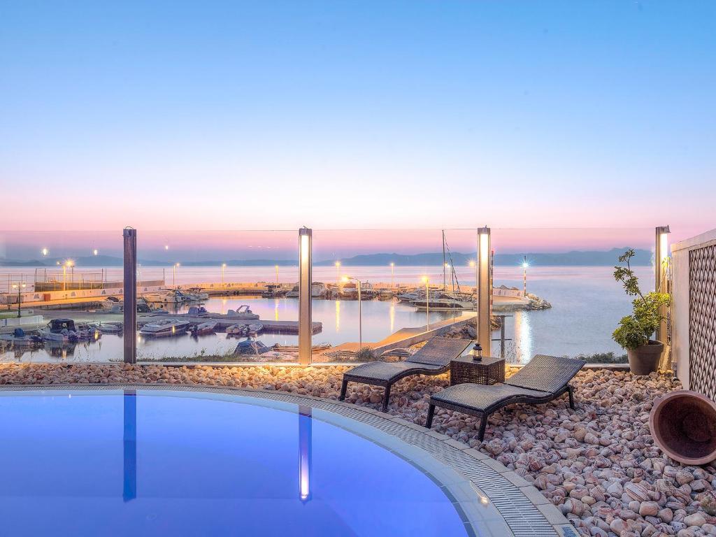 a swimming pool with benches and a view of a harbor at Cabo Verde Hotel in Mati