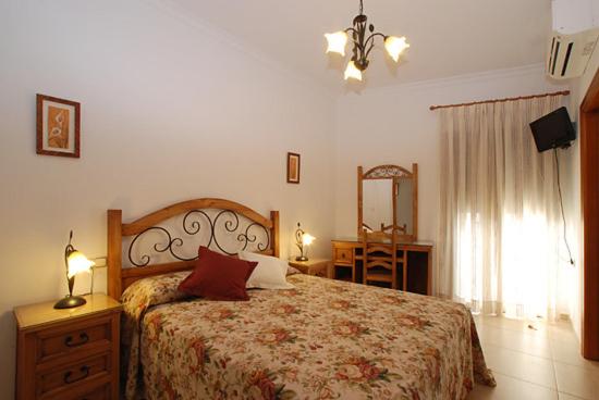 a bedroom with a bed and a dresser and a mirror at Hostal el Puente in Tabernas