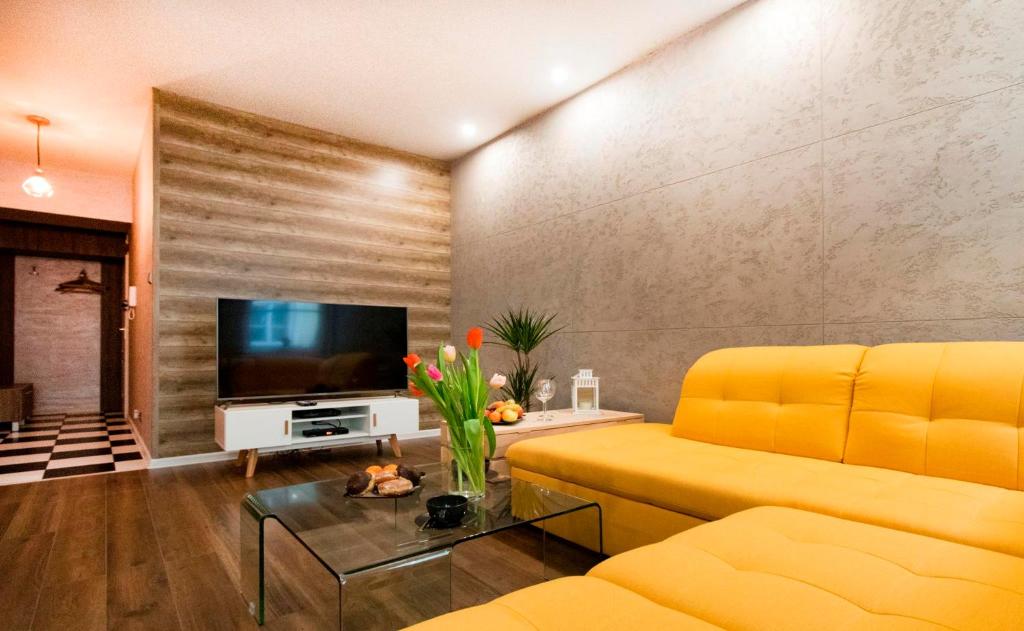 a living room with a yellow couch and a television at Prestigious Main Square Apartment in Kraków