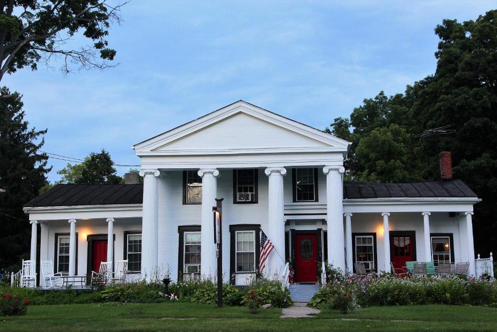 a white house with a red door and an american flag at Glass Magnolia Bed & Breakfast in Interlaken