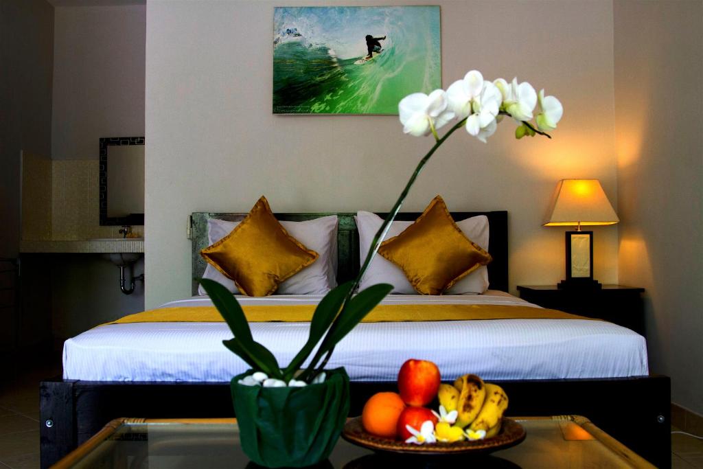 ein Schlafzimmer mit einem Bett mit einer Schale Obst auf einem Tisch in der Unterkunft Ropik & Alik Home Stay in Uluwatu