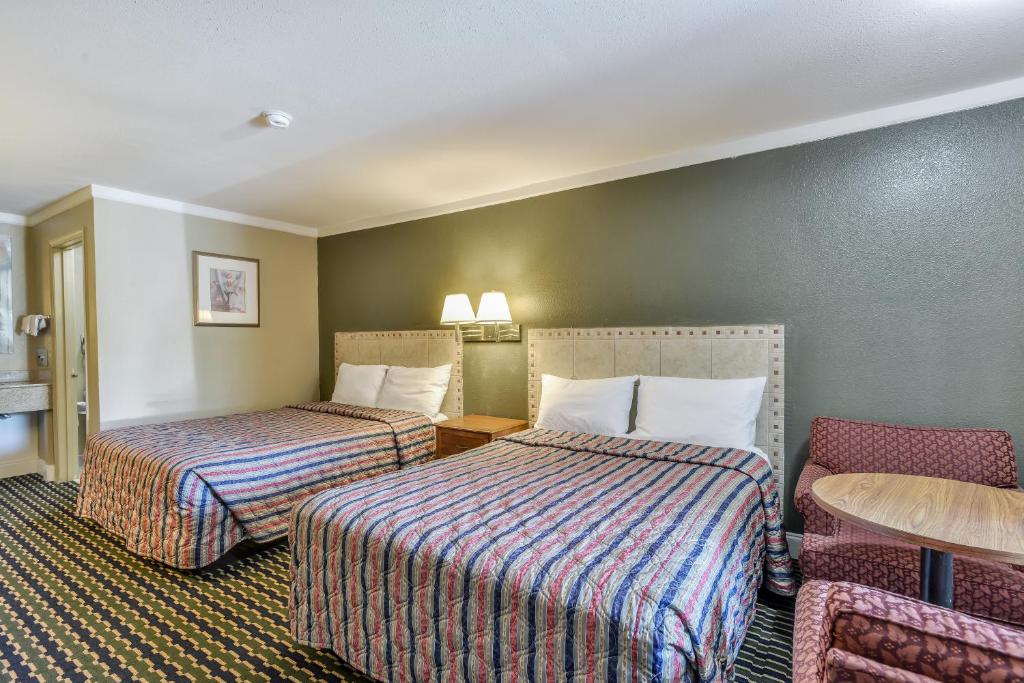 Habitación de hotel con 2 camas, mesa y sillas en Wake Inn, en Raleigh
