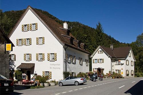 ein großes weißes Gebäude mit einem davor geparkt in der Unterkunft Landgasthof St. Luzisteig in Maienfeld