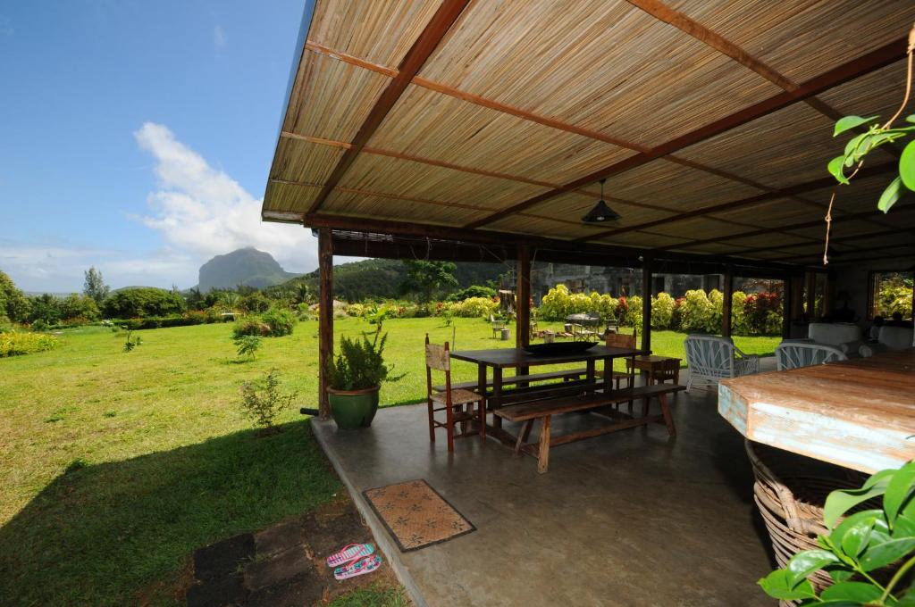 a patio with a table and chairs under a roof at The Kiter’s Nest Baie du Cap in Choisy