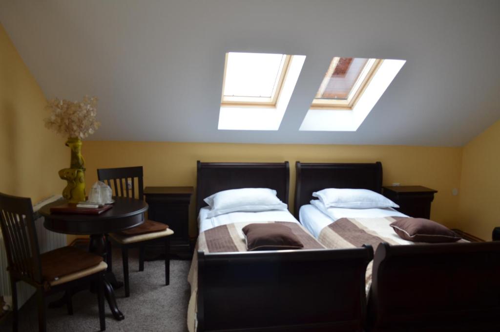 a bedroom with two beds and a table and skylights at Pensiunea Koruna in Poenari