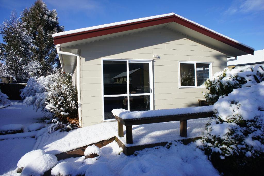 una panchina nella neve davanti a una casa di Holiday Chalet a National Park