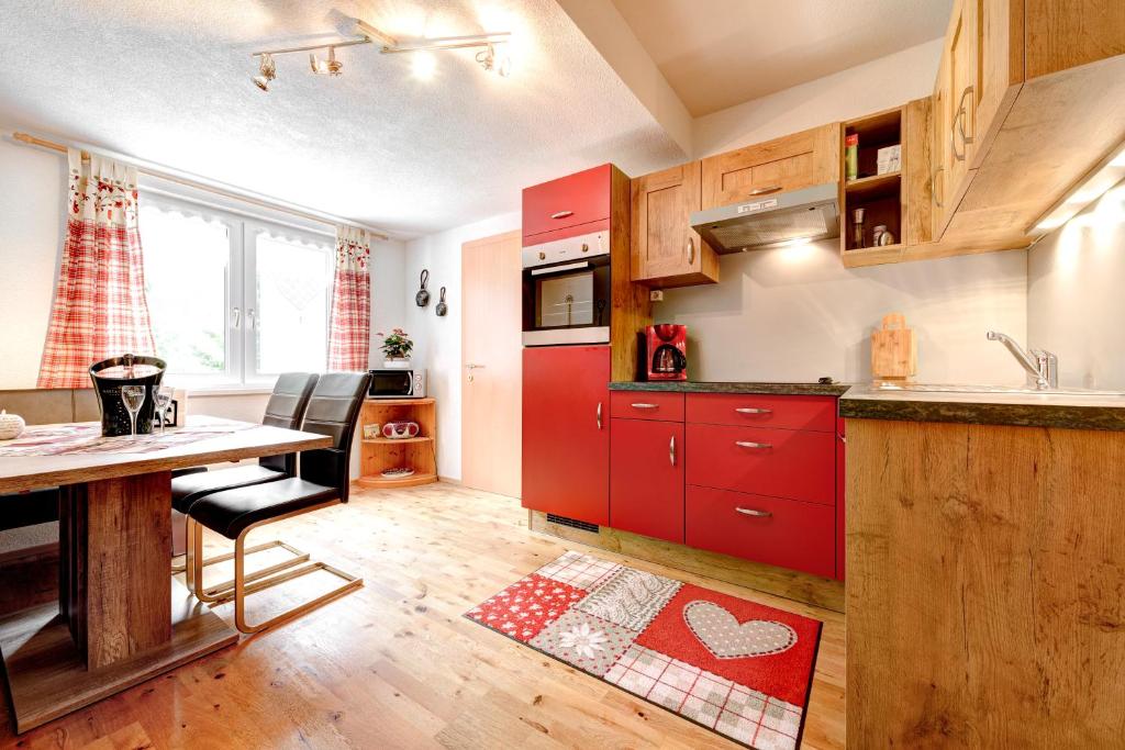 a kitchen with red cabinets and a table and chairs at Haus Edelweiss in Brand