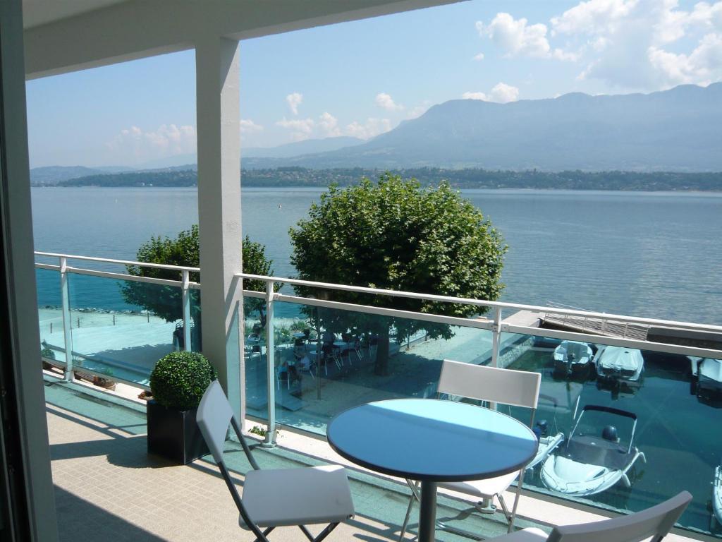 balcone con tavolo, sedie e vista sull'acqua di Les Suites du Port a Le Bourget-du-Lac