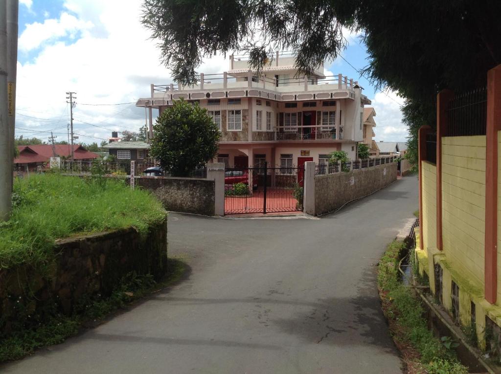 a large house with a gate in front of a street at Holly Lodge Guest House in Shillong