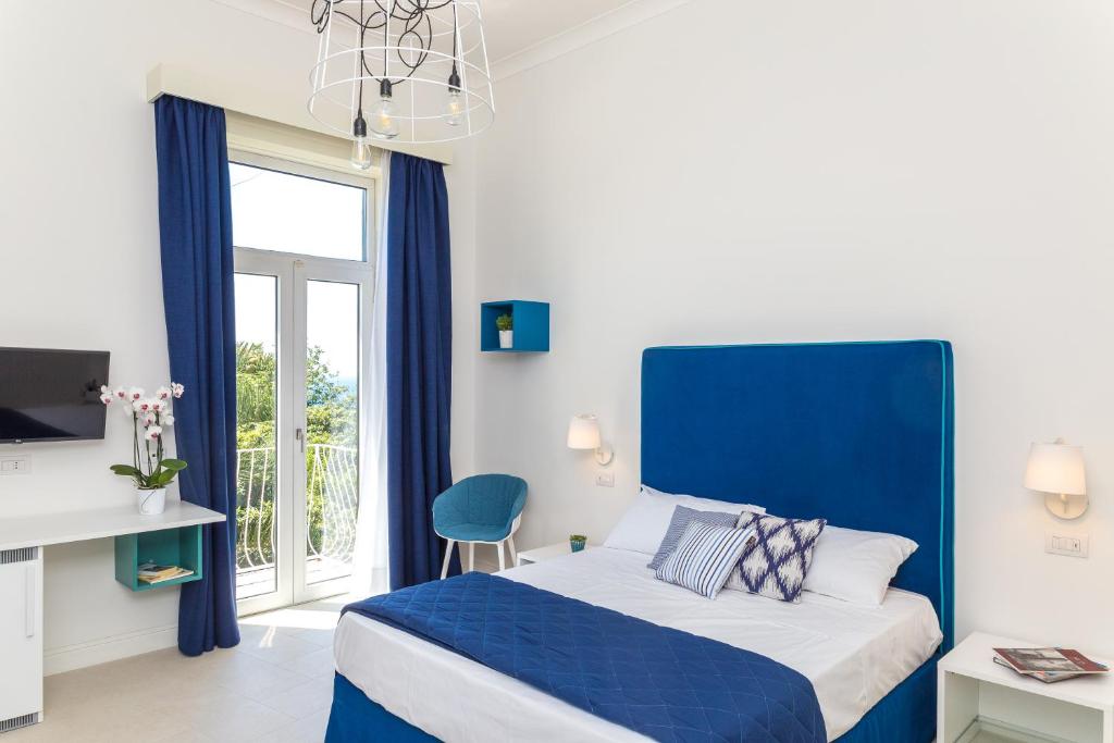 Maison Ro' في ميتا: غرفة نوم زرقاء وبيضاء مع سرير ونافذة