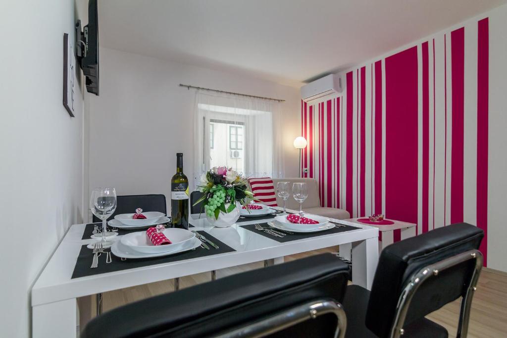 a dining room with a white table and pink walls at Apartments Trend 2 in Rijeka