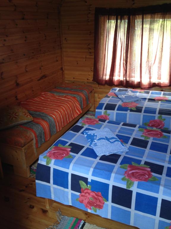 two beds in a wooden cabin with flowers on them at Little Garden House in Kassari
